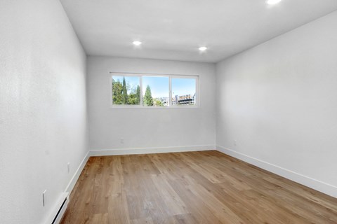 A room with a window showing a view of trees and buildings outside.