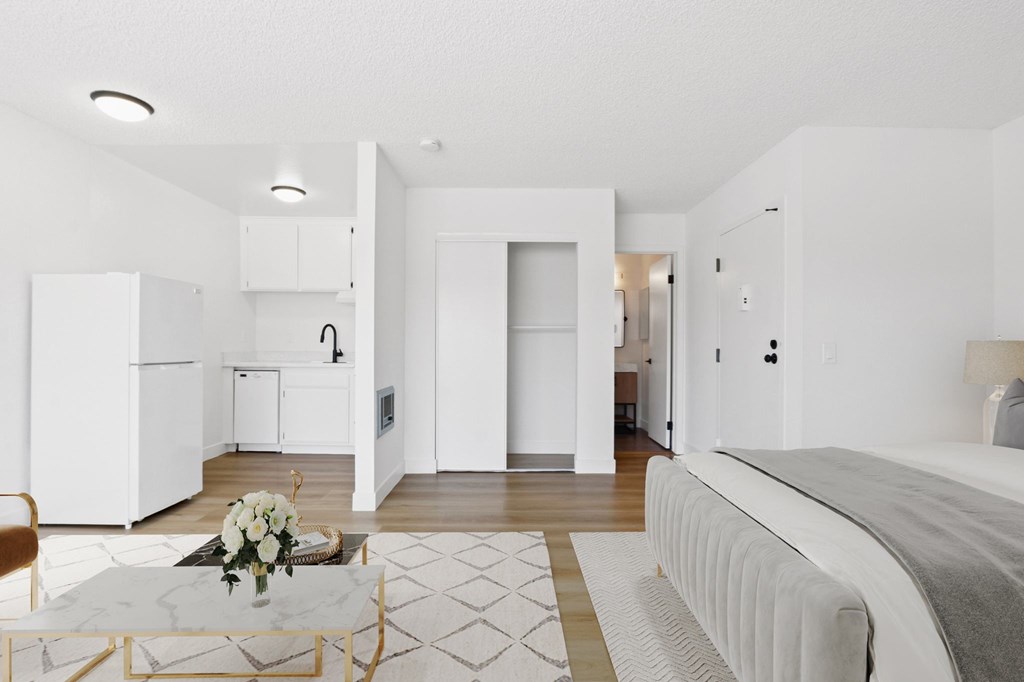 A white bedroom with a bed, a table, and a chair.