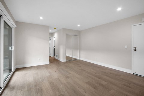 A spacious room with wooden flooring and white walls.