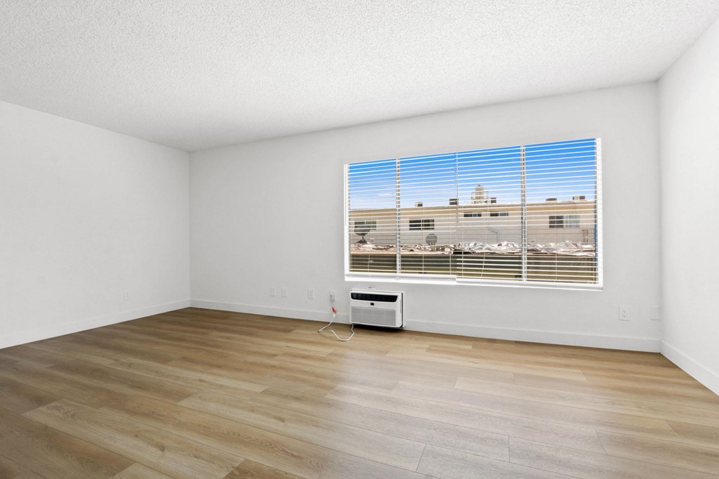 A room with a window overlooking a parking lot.