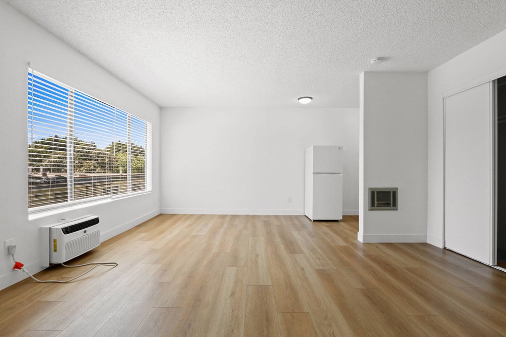 A room with wooden floors and a window with blinds.