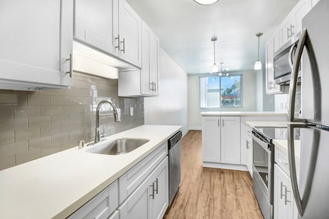 A kitchen with white cabinets and a stainless steel refrigerator.