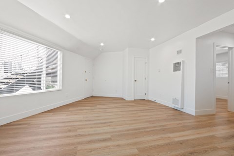 A spacious room with wooden flooring and white walls.