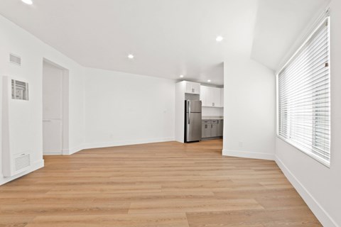 A kitchen with white cabinets and a wooden floor.