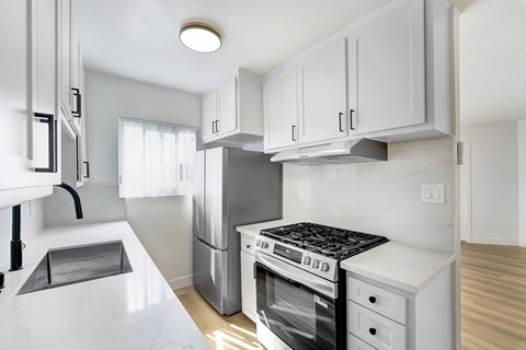 A modern kitchen with white cabinets and appliances.