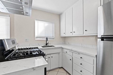a kitchen with white cabinets and a stove and a sink