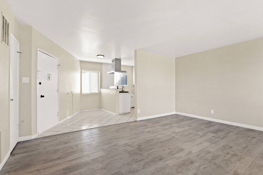 the living room and kitchen of an empty apartment with wood flooring