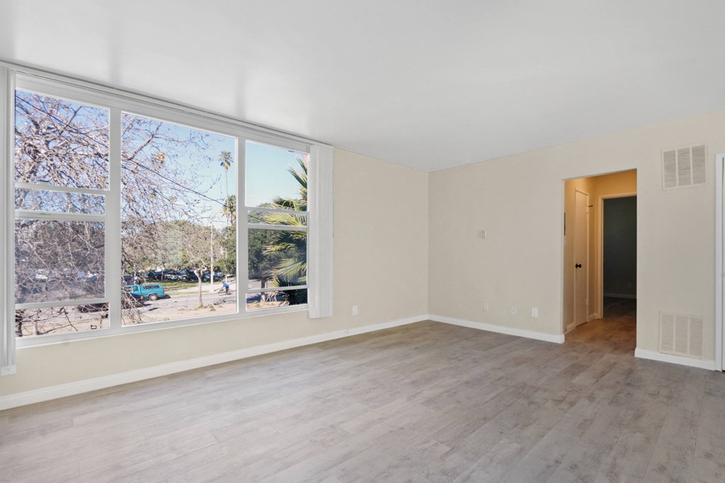 an empty living room with large windows and wood flooring