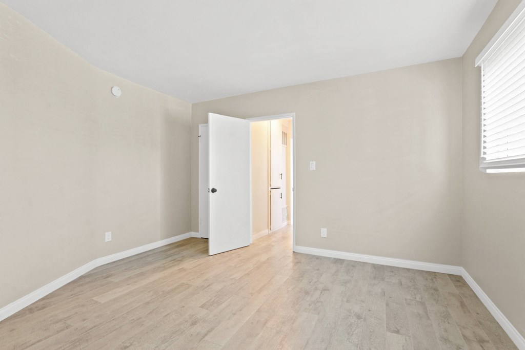 an empty living room with wood flooring and white walls