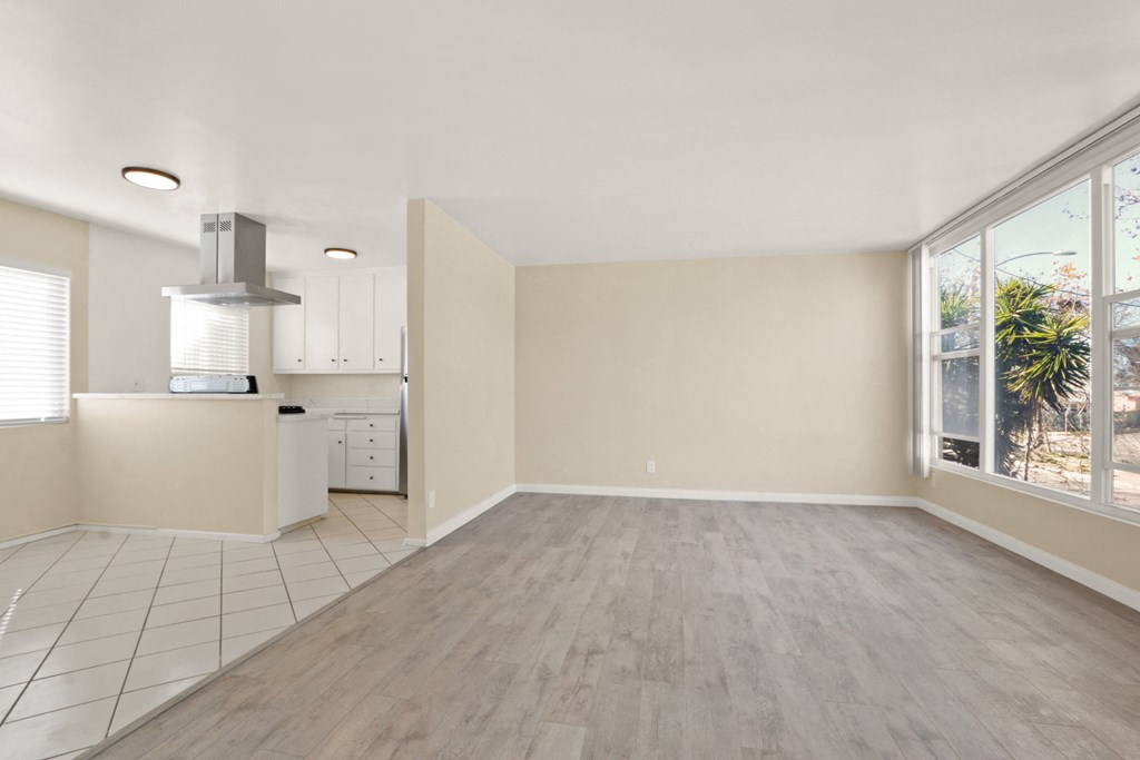 an empty living room and kitchen with a large window