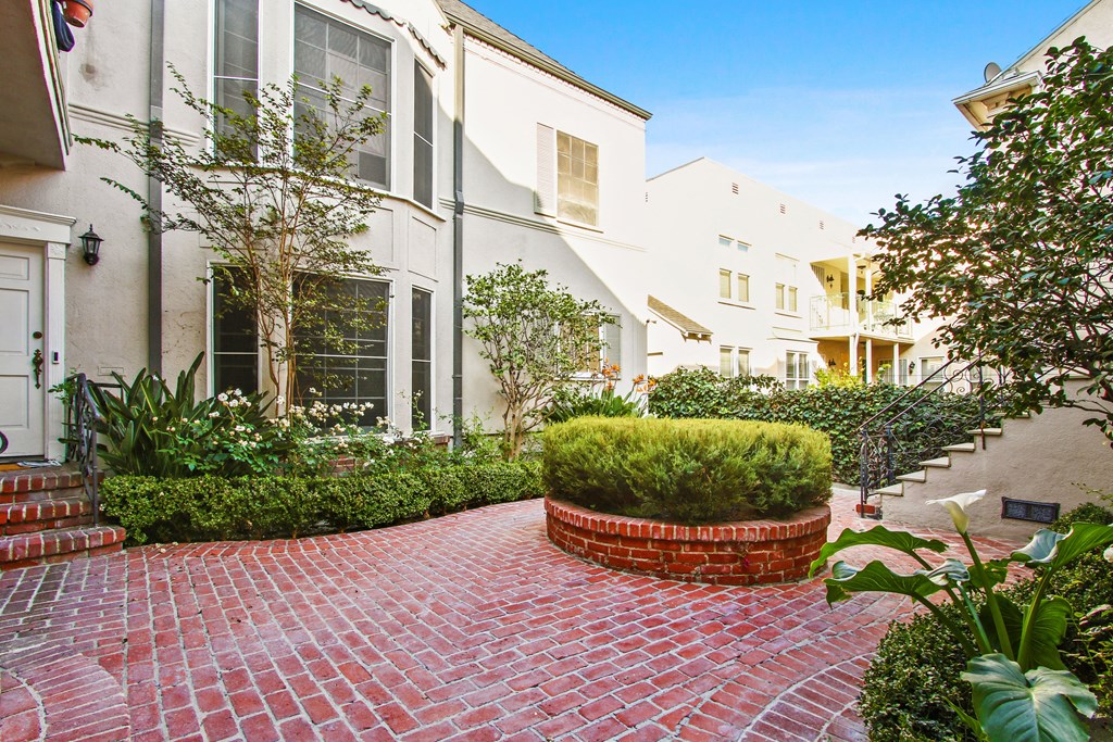 a courtyard with a red brick path and a white building