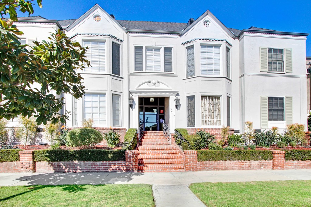 the front of a white house with stairs and a driveway