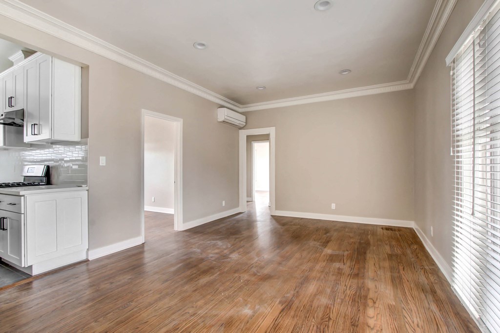 an empty living room and kitchen with wood flooring and a window