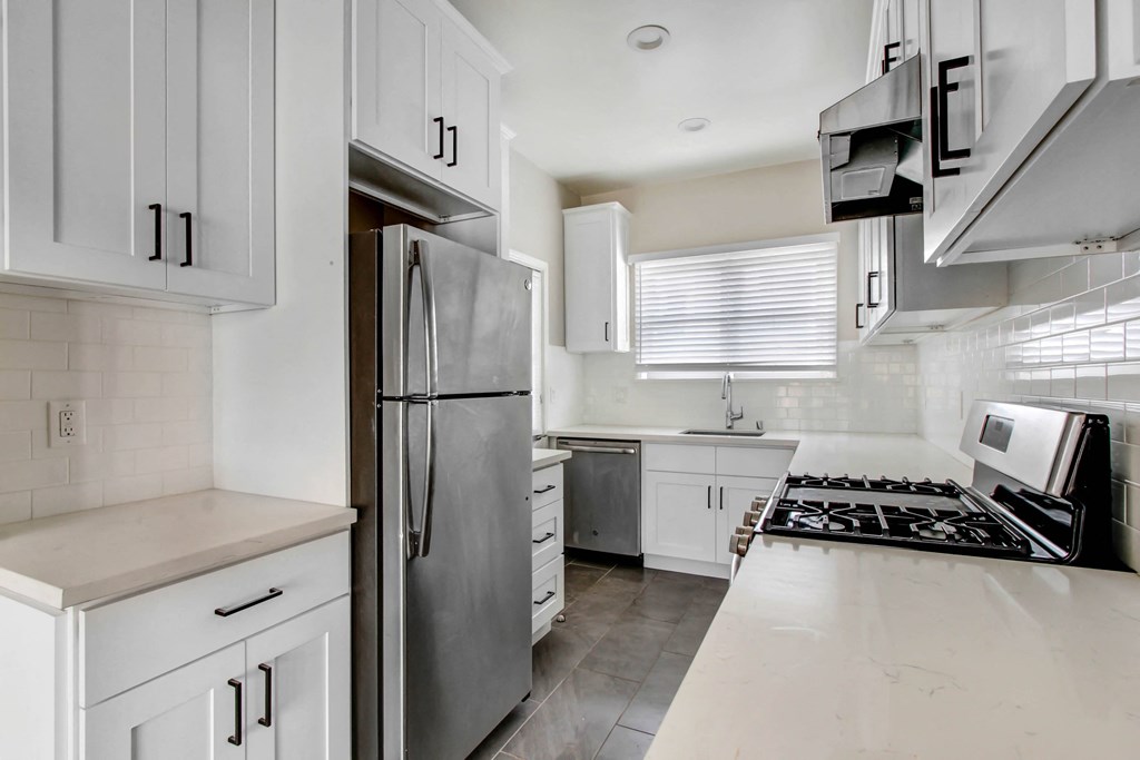 a white kitchen with stainless steel appliances and white cabinets