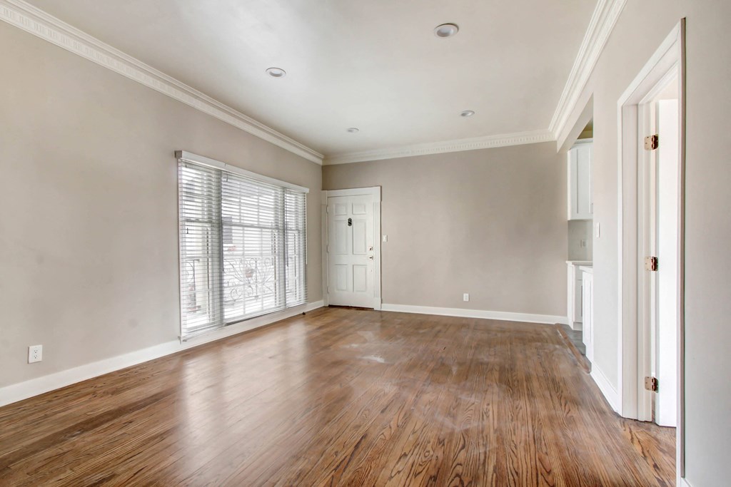 an empty living room with wood floors and white walls