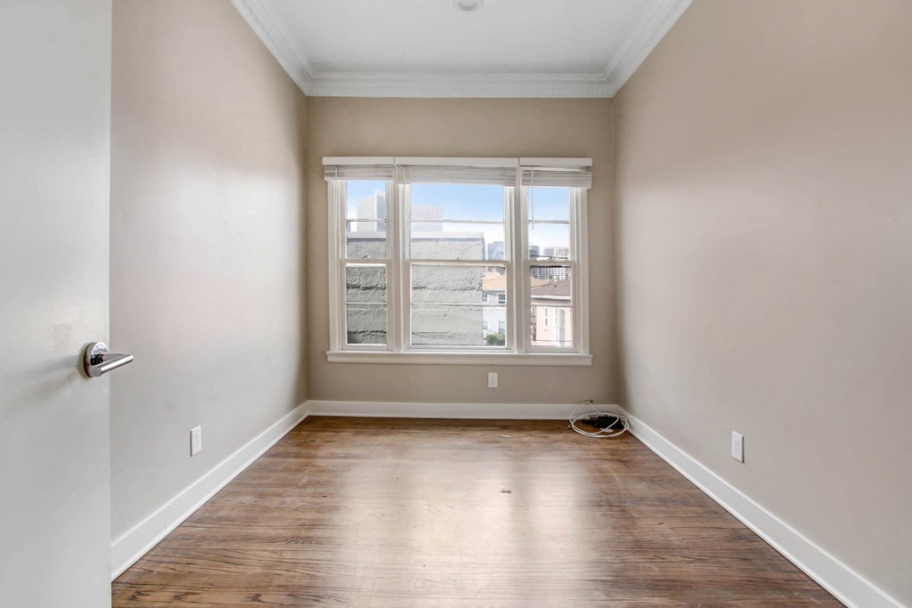 a empty room with a window and wooden floors
