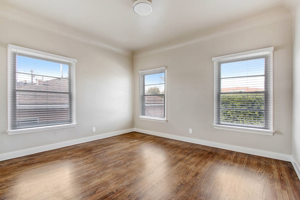 an empty living room with wood floors and two windows