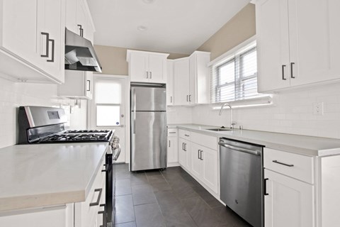 A modern kitchen with white cabinets and stainless steel appliances.