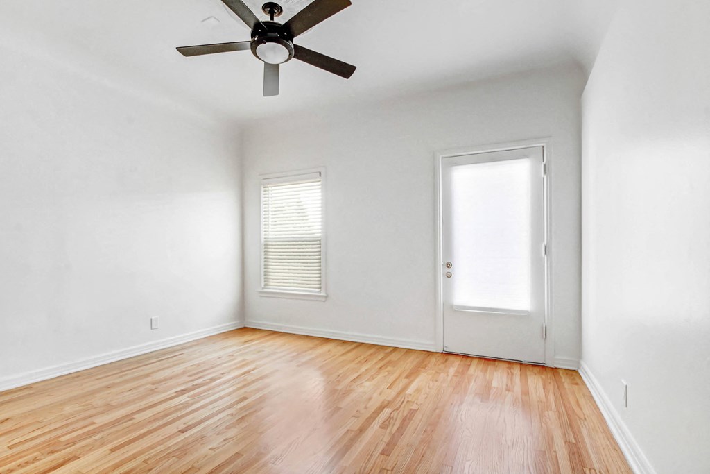 an empty living room with wood floors and a ceiling fan