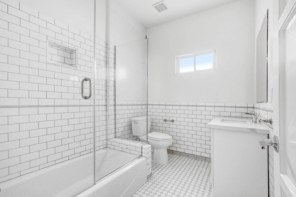 a white bathroom with a shower toilet and sink