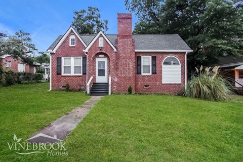 A brick house with a chimney and a sign that says Vinebrook Homes.