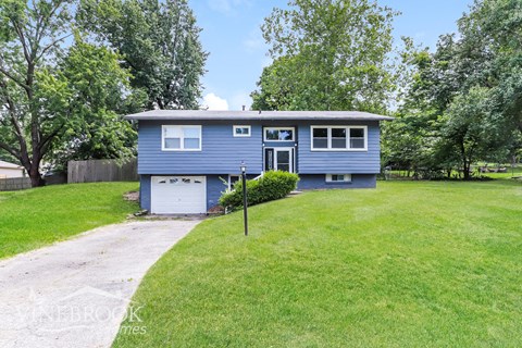 a blue house with a yard and a driveway