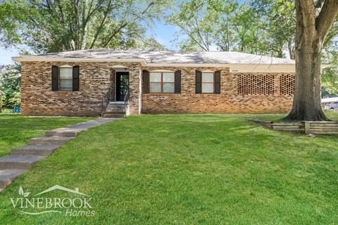 a small brick house with a lawn and a tree