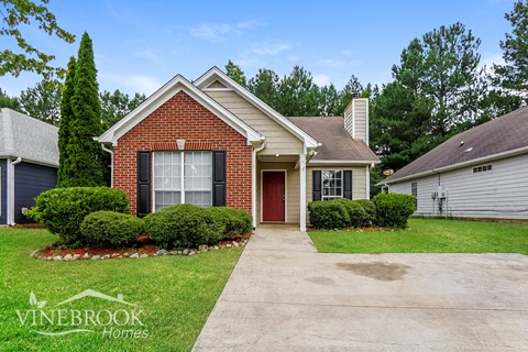 a small brick house with a sidewalk in front of it