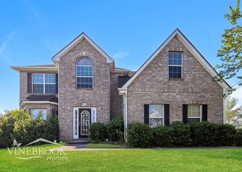 a large brick house with a green lawn in front of it