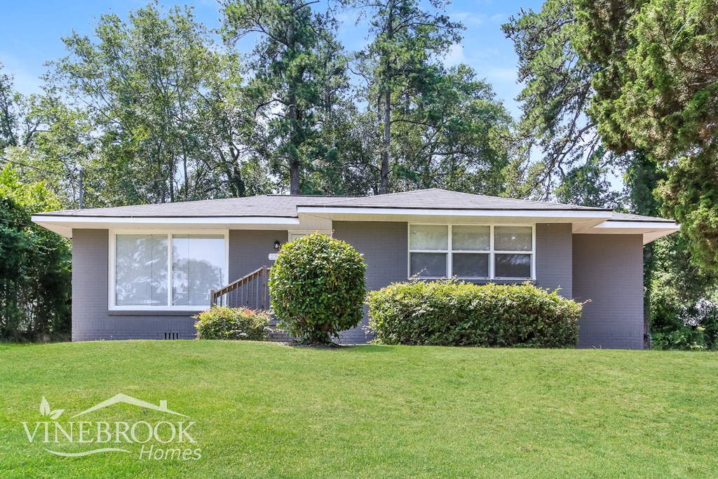 A house with a well-kept lawn and trees in the background.
