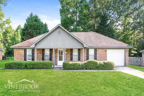 a small brick house with a lawn in front of it