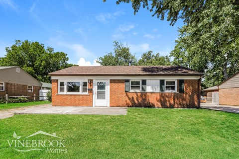 a small brick house with a lawn in front of it
