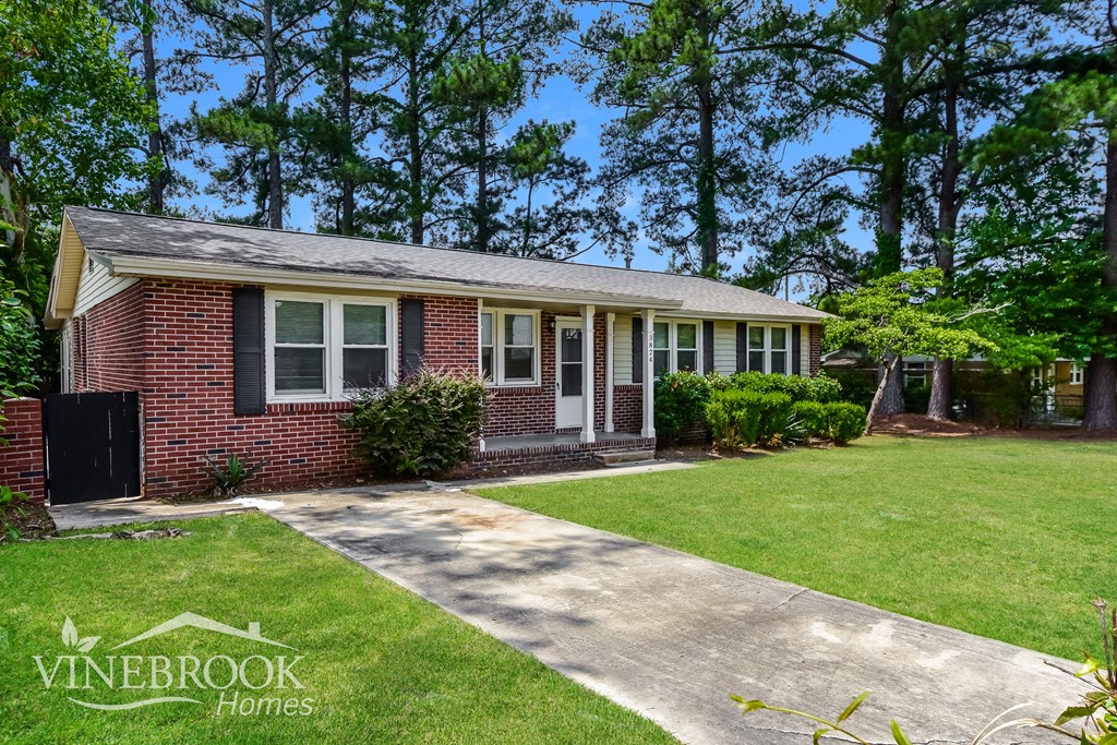 a small brick house with a lawn and a driveway