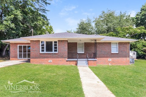 a small brick house with a lawn in front of it