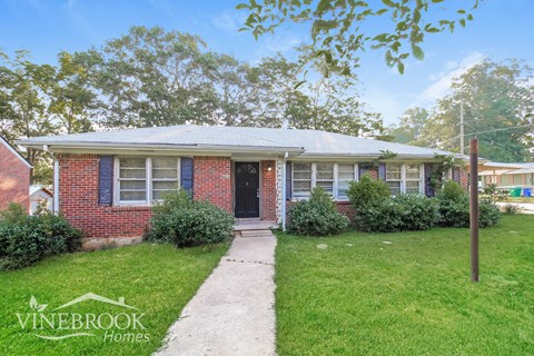 a small brick house with a sidewalk in front of it