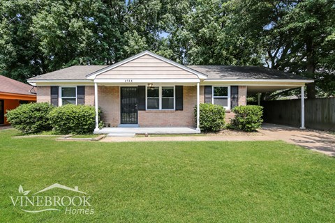 a small brick house with a lawn in front of it