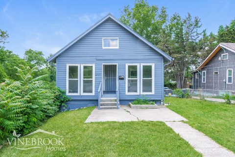 a blue house with a sidewalk in front of it