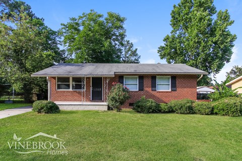 a small brick house with a lawn in front