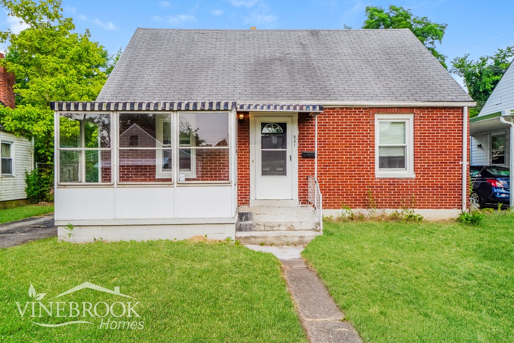 a white and red brick house with a porch and grass