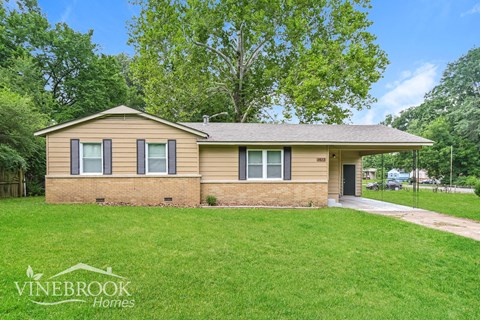 a small brick house with a grassy yard