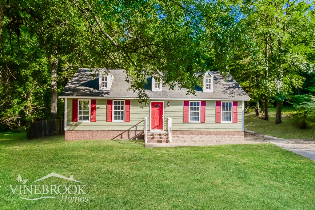 a small red and white house with red doors and a lawn