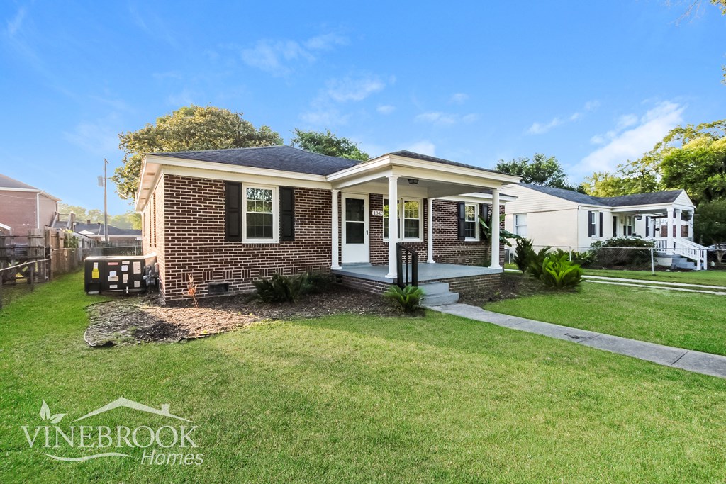 a small brick house with a lawn and a sidewalk