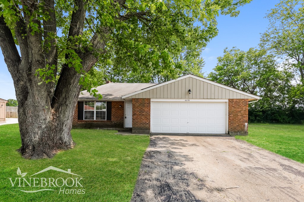 a brick house with a white garage door and a tree