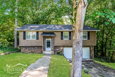 a small brown house with a tree in front of it