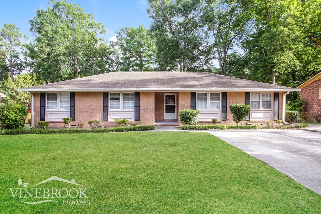 a small brick house with a lawn and a driveway
