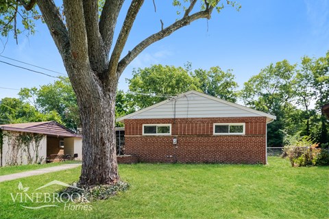 a brick house with a tree in the yard