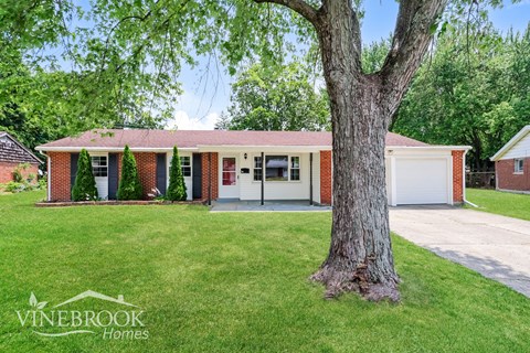 a home with a large tree in front of it