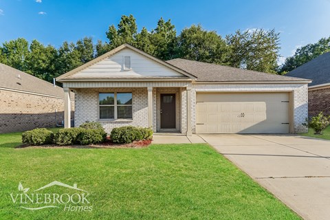 a white brick house with a garage and a lawn