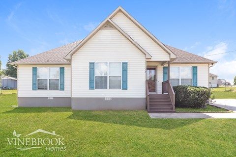 a white house with blue shutters and a lawn