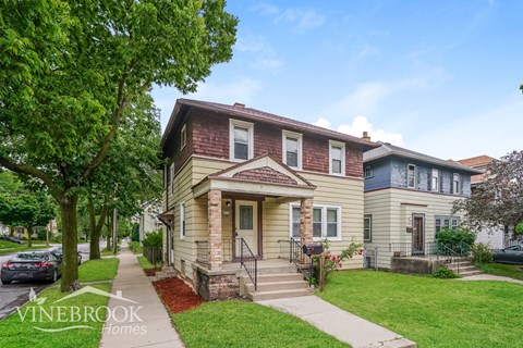 a yellow house with a red brick facade and a tree